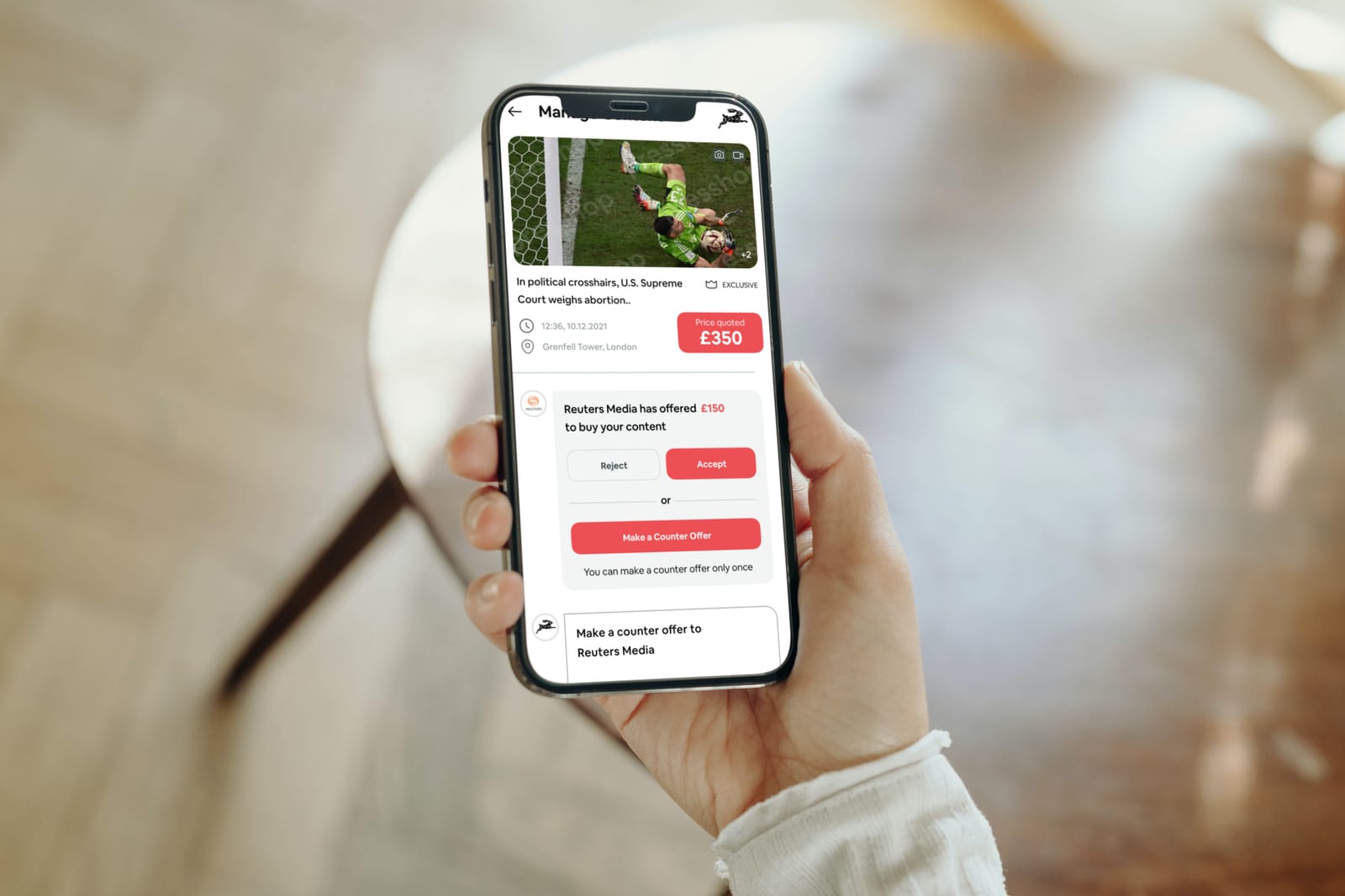 A woman holding a mobile phone with the PRESSHOP app opened on it